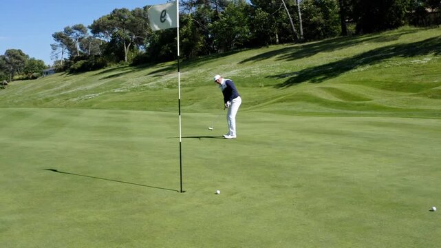 Golfer practicing putting skills on sunny day at beautiful golf course