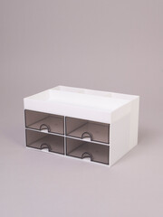 Empty white stationery and cosmetics organizer with four drawers on gray background
