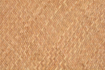 A uniform full-frame background of tightly woven natural light brown straw, reed, or bamboo material with a distinctive zigzag pattern