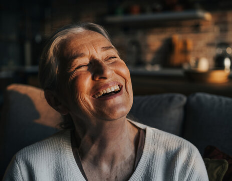 Elderly woman laughing with eyes closed.