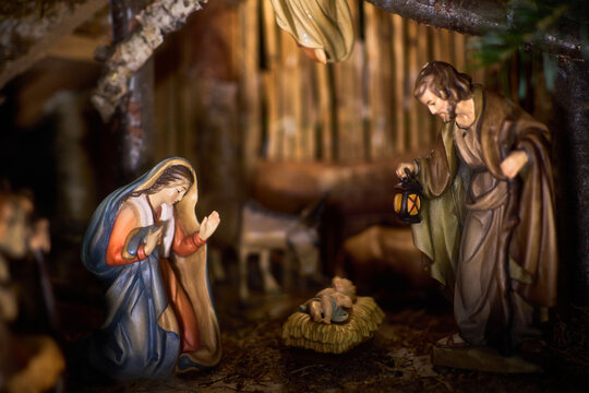 An antique wooden Christmas Nativity set with the holy family gazing at baby Jesus. The scene of the birth of Jesus Christ in the stable.