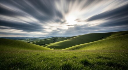 Rolling green hills under a dramatic sky with sun rays.