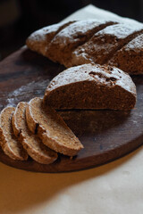 Rustic whole wheat artisan bread placed on a wooden board, with several slices in foreground. Warm natural light and soft shadows highlight the texture and handmade quality.