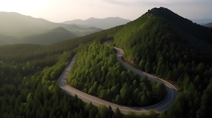 Winding road snakes through a densely forested mountain landscape at dawn