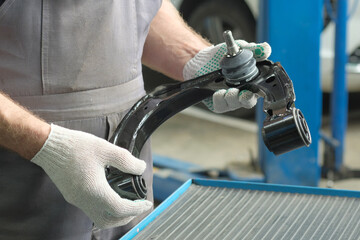 Obraz premium Car service.An auto mechanic is preparing to replace the front suspension arm.A new spare part is in the hands of a specialist, control, inspection, diagnostics of the serviceability and integrity of 