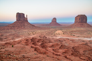 Panoramic view of Monument Valley desert landscape under bright summer sun and clear blue sky