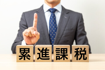 「累進課税」と書かれたブロックとビジネスマン