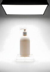Minimalist product photography of a white pump bottle on a clear stand with bright overhead studio lighting.