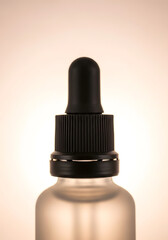 Close-up shot of a frosted glass bottle with a black dropper, illuminated against a soft background.