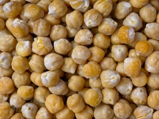 A detailed, close-up view showing a dense, full-frame pile of light yellow to tan chickpeas (garbanzo beans).