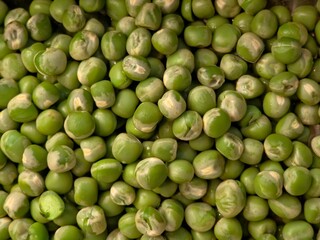 A detailed, close-up view showing a large pile of fresh or frozen green peas, featuring variations in color and texture.