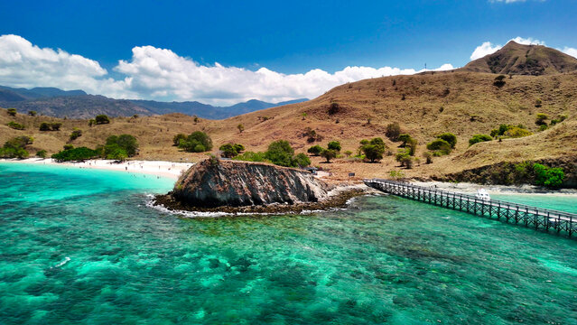 Scenic overhead aerial landscape of Komodo Island’s Pink Beach surrounded by lush green hills