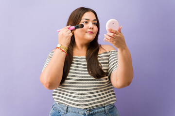 Overweight woman applying makeup looking in mirror