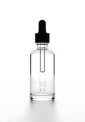 A clear glass dropper bottle with a black cap and a clear liquid inside, isolated on a white background.
