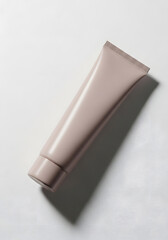 A minimalist studio shot of a single dusty pink cosmetic tube on a white background with a strong shadow.