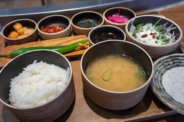 A bowl of rice, and soup with various Korean side dishes.