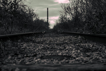 Abandoned railway tracks in autumn with industrial background black and white