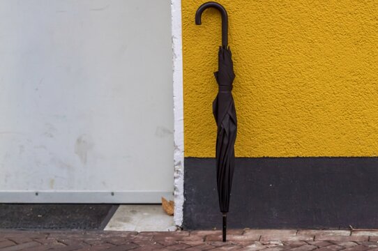 Black umbrella leaning against colorful urban wall