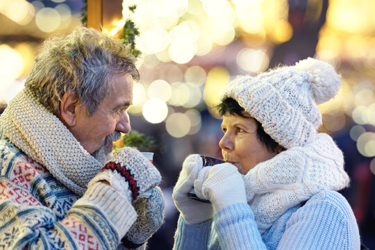 winter holidays, hot drinks and people concept - happy senior couple with coffee at christmas market in evening