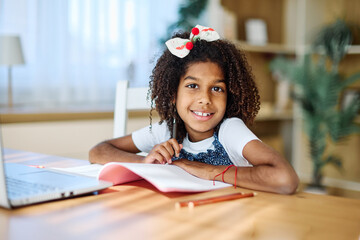 Portrait of a teenage girl having fun using laptop writing and doing homework with laptop at home