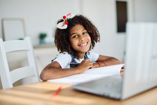 Portrait of a teenage girl having fun using laptop writing and doing homework with laptop at home