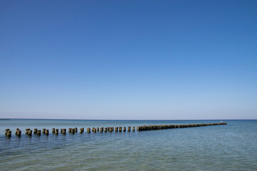 Drewniany falochron pod błękitnym niebem © Sebastian