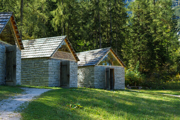Several stone brick mountain houses with a wooden roof in the Austrian Alps against the backdrop of a dense forest