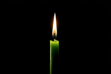 Single green candle flame burning brightly against a stark black background