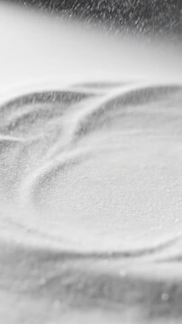 Extreme close-up slow motion shot of fine white sand particles rhythmically vibrating and settling on a blank minimalist surface abstract, backdrop, concept