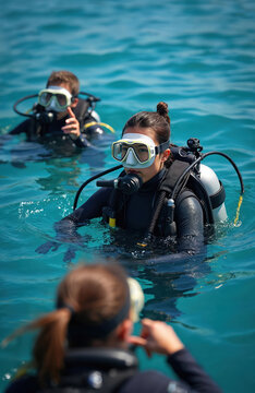 Scuba divers prepare for dive in clear blue water. Instructor guides new students learning underwater exploration. People wear masks fins suits oxygen tanks for ocean adventure.
