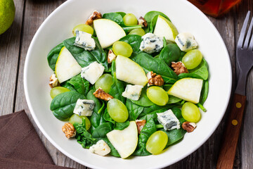 Salad with spinach, blue cheese, pear, grapes, and nuts. Healthy eating. Vegetarian.