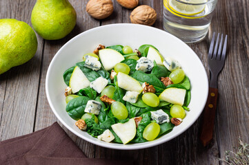 Salad with spinach, blue cheese, pear, grapes, and nuts. Healthy eating. Vegetarian.