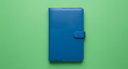 A closed blue leather notebook with a strap closure placed on a solid green background, suitable for organization or note-taking purposes