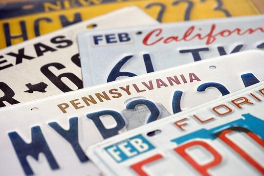 Old US car license plates with various state names close up. Concept of driving in United States. Reaching a car registration