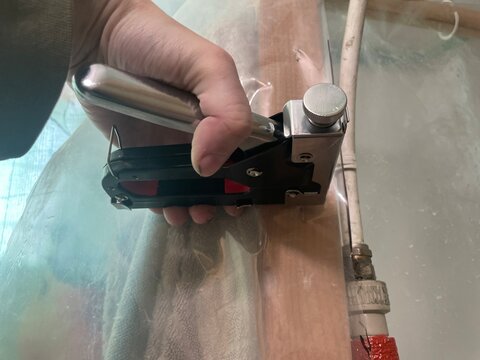Construction staple gun fixing plastic sheet