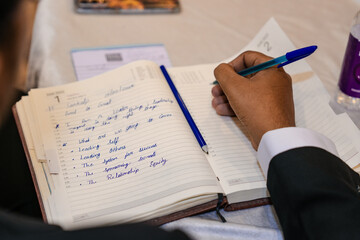 Hand writing notes in an open notebook during a learning or planning session, suitable for business, study, and productivity themes.