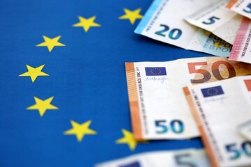 Many euro money bills banknotes on flag of European Union. Concept of business and finances in Europe