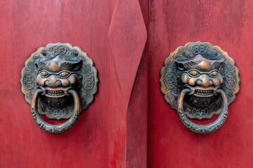 Ornate metal door knockers adorn the doors of one of the buildings at the Buddhist temple of Wat Ratcha Orasaram Ratchaworawihan in Bangkok, Thailand. 
