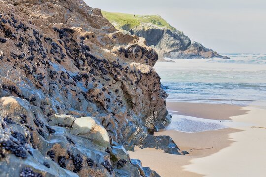 A rocky coastal scene with the tide rolling in. Rugged cliffs meet the sandy beach, with the ocean stretching to the horizon in Polly Joke - Cornwall - UK - Powered by Adobe