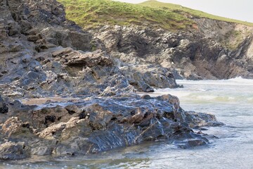 Coastal rock formations dominate the foreground, showcasing intricate textures and varying shades of grey and tan in Polly Joke - Cornwall - UK