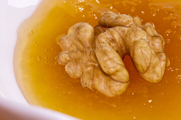 Peeled walnut soaked in a vessel with natural honey, macro shot.