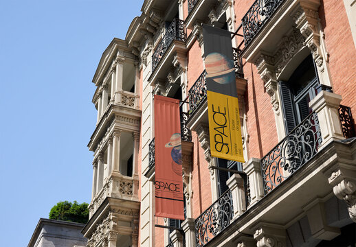Fly banners hang from elegant buildings in Madrid, adding a modern touch to the historic architecture on a clear day. PSD template mockup