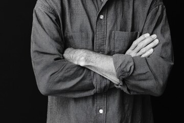 Confident Stance: A grayscale depiction of a person with folded arms, conveying a sense of self-assurance and composure against a backdrop of stark contrast.