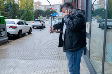 Man talking on phone checking wallet on city street