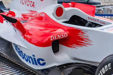 Naklejka premium Indoor shot of a red Toyota F1 car TF-108 with white accents and black stripes, featuring brand logos for Toyota, Denso, and Sony Prepared for dry conditions with s - Kyiv, Ukraine 10-10-2024