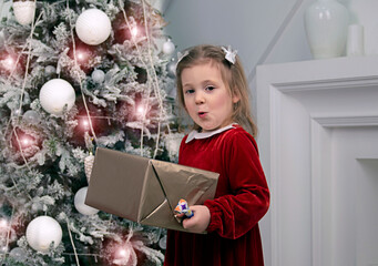 a little girl holds a Christmas gift box