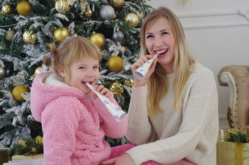 mom and daughter happily playing and having fun near the Christmas tree