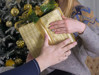 a young woman hands a box . wrapped in gift paper , a gift to a man