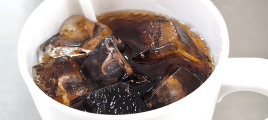 Black soda and ice in a glass.