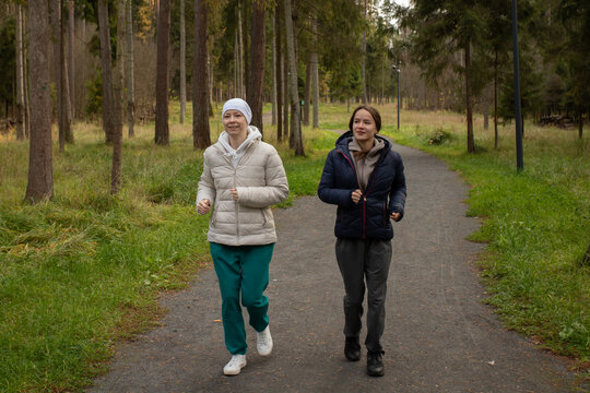 Cancer survivor running outdoors with companion, concept of motivation, endurance, and physical rehabilitation after chemotherapy.